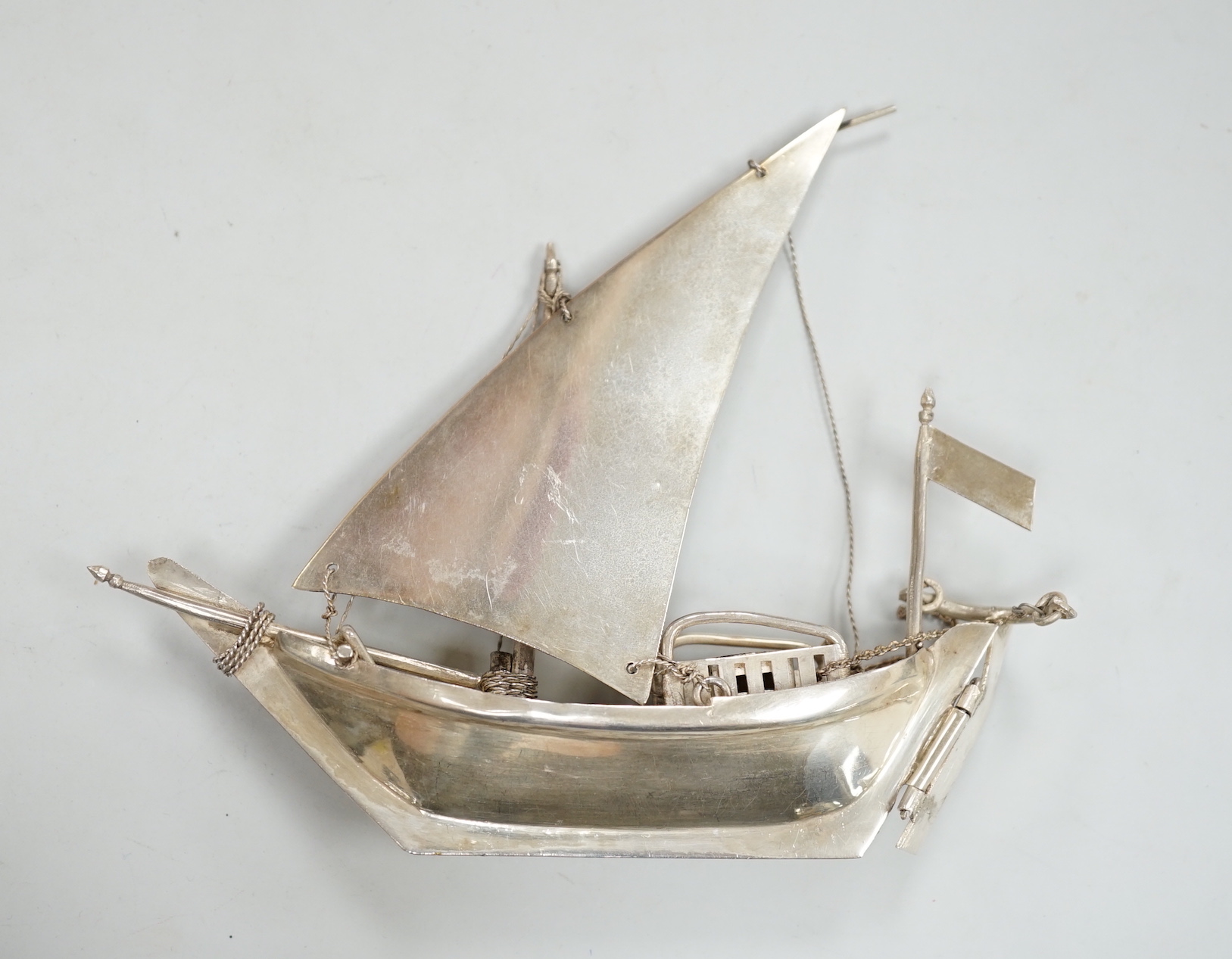 A Kuwait white metal miniature model of a sail boat, length 16cm, on wooden stand